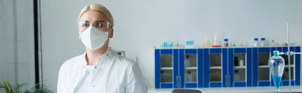 Cientista em máscara protetora e óculos olhando para a câmera em laboratório, banner — Fotografia de Stock