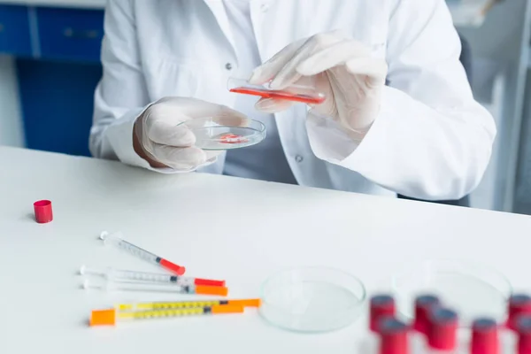 Cropped view of scientist pouring liquid from test tube on petri dish in lab — Foto stock