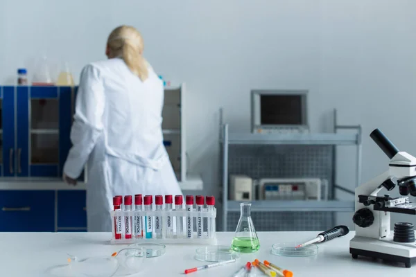 Back view of scientist working near test tubes with monkeypox lettering and microscope in lab — стоковое фото