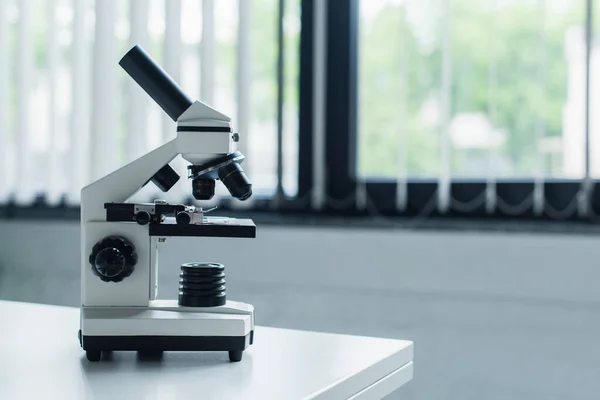 Microscope on white table in blurred laboratory — Photo de stock