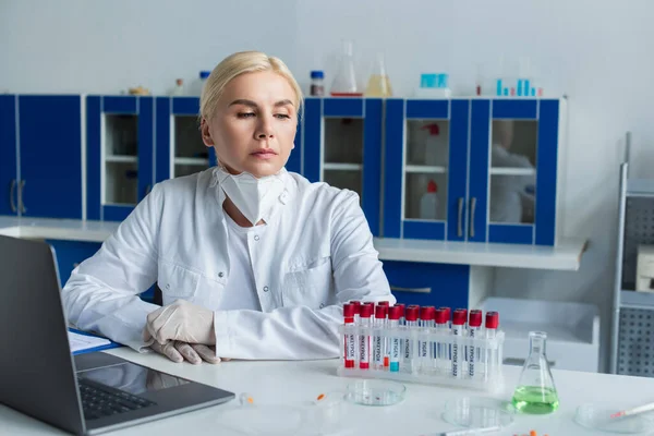 Scientist looking at test tubes with monkeypox lettering near laptop in lab — Photo de stock