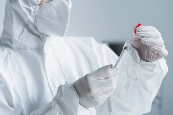 Обрізаний вигляд вченого в костюмі з туманом в латексних рукавичках, що тримає шприц в лабораторії — стокове фото