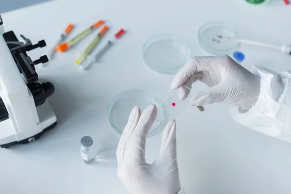 Cropped view of scientist holding glass near petri dishes and microscope in lab — Stockfoto