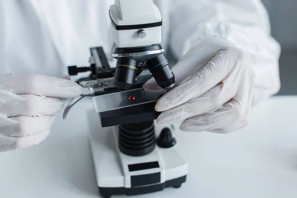 Vista recortada do cientista em luvas de látex usando microscópio em laboratório — Fotografia de Stock
