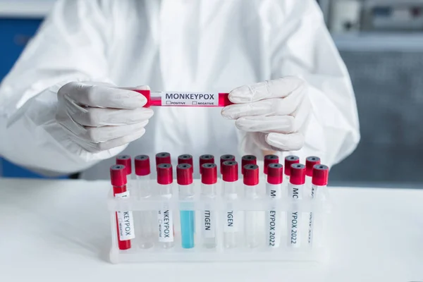 Vista cortada do cientista em terno hazmat segurando tubo de ensaio com letras de varíola em laboratório — Fotografia de Stock