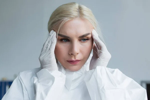 Scientist in protective suit suffering from headache in lab — Fotografia de Stock