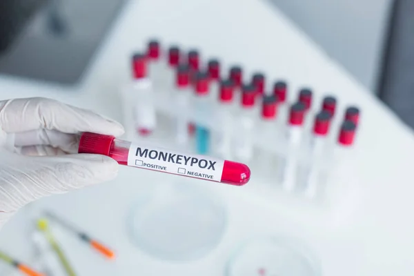 Cropped view of scientist in latex glove holding test tube with monkeypox lettering in blurred laboratory — Photo de stock