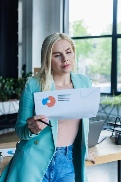 Blonde psychologist holding paper and pen in consultation room — Stock Photo