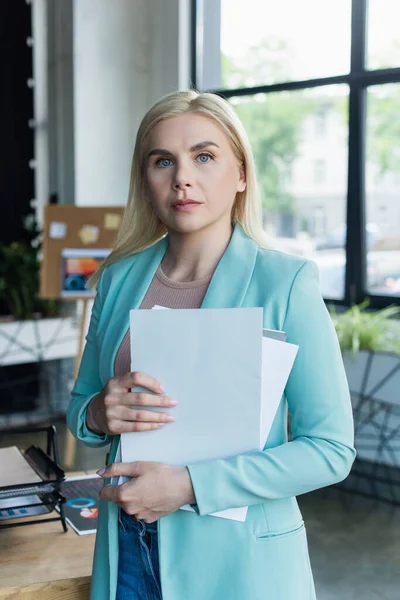 Psychologe hält Dokumente in der Hand und blickt in die Kamera im Beratungsraum — Stockfoto