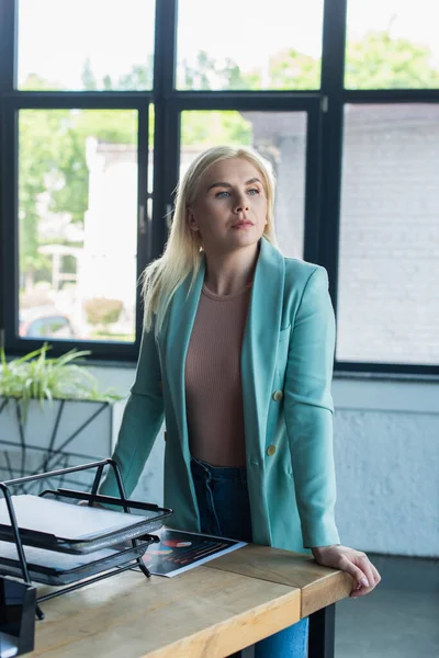 Blonde psychologist standing near papers on table in consultation room — Foto stock