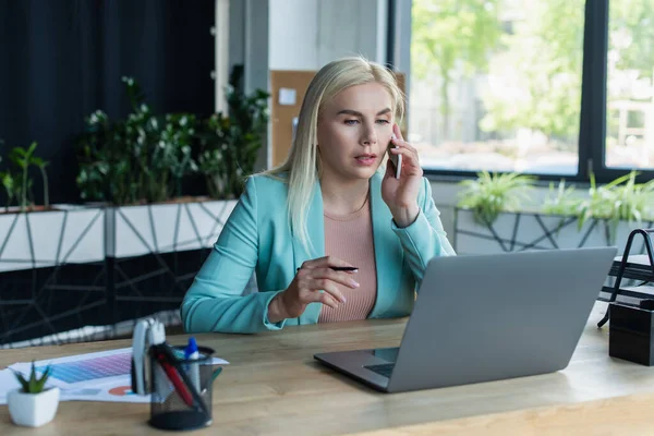 Psychologist talking on smartphone near laptop in consultation room — Fotografia de Stock