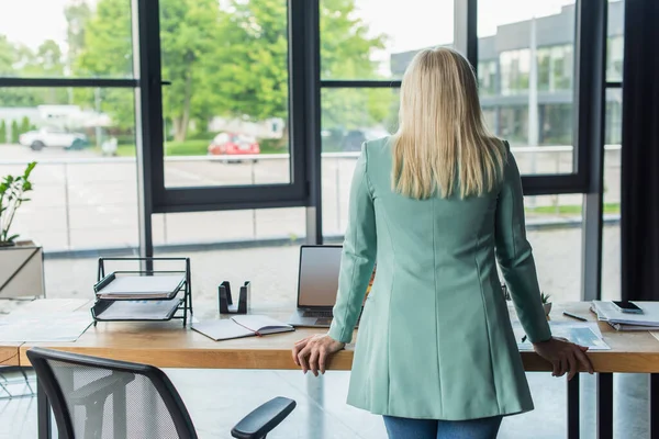 Rückenansicht eines Psychologen, der neben Laptop und Papieren auf dem Tisch im Beratungsraum steht — Stockfoto