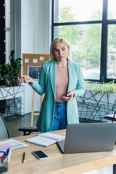 Psychologist having video call on laptop near notebook in consultation room - foto de stock