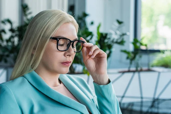 Blonde psychologist holding eyeglasses in consultation room — Stockfoto