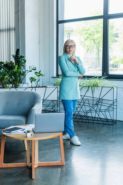 Psychologe mit Brille blickt im Sprechzimmer auf Laptop — Stockfoto