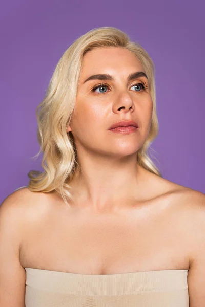 Blonde woman with bare shoulders looking away isolated on purple — Fotografia de Stock