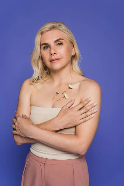 Blonde woman with plasters and white flowers on body looking at camera isolated on purple — Fotografia de Stock