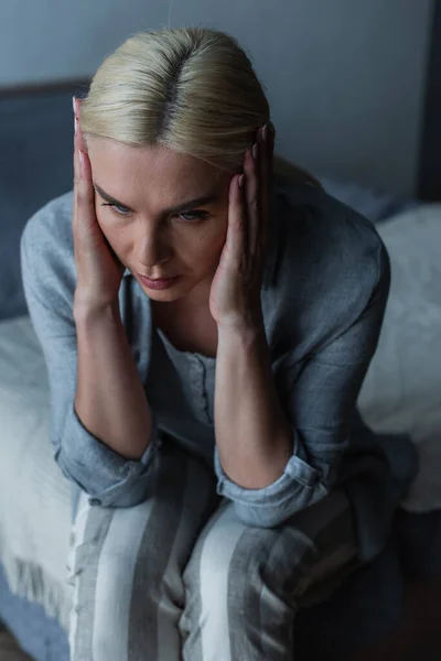 High angle view of exhausted blonde woman with menopause suffering from headache in bedroom — Fotografia de Stock