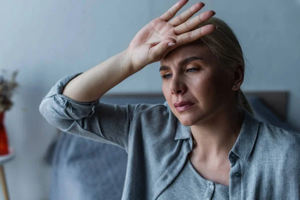 Mulher loira cansada com menopausa sofrendo de calor no quarto — Fotografia de Stock