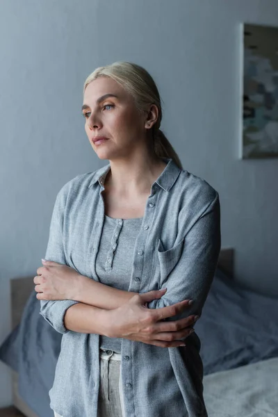 Donna depressa con menopausa in piedi con le braccia incrociate e distogliendo lo sguardo — Foto stock