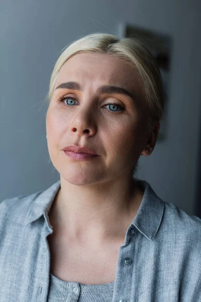 Retrato de la mujer molesta con los ojos azules se sienten preocupados debido a la menopausia - foto de stock