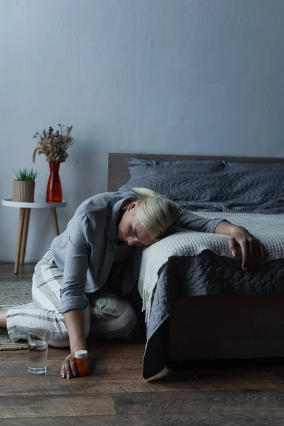 Exhausted woman having menopause and holding bottle with painkillers while suffering from pain — Fotografia de Stock