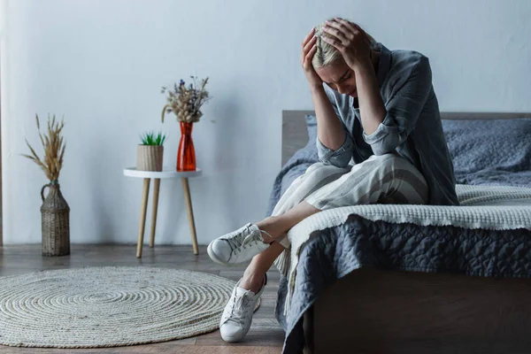 Blonde woman touching head while suffering from pain during menopause — Stock Photo