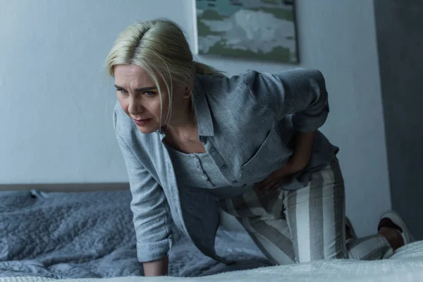 Mulher loira tocando barriga enquanto sente dor no estômago durante a menopausa — Fotografia de Stock