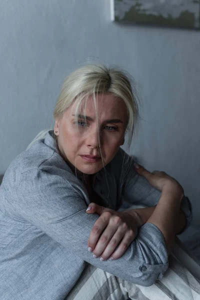 Blonde and depressed woman with blue eyes feeling unwell during menopause - foto de stock