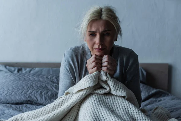 Depressed blonde woman with menopause holding blanket while in bed — Foto stock