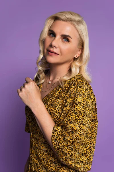 Портрет улыбающейся блондинки в блузке, позирующей изолированно на фиолетовом — стоковое фото