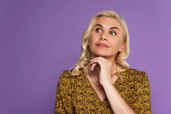 Perplesso donna bionda in camicetta guardando lontano isolato su viola — Foto stock