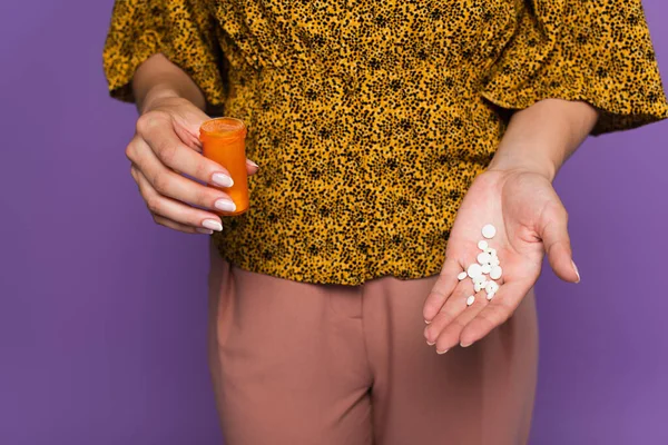 Vista cortada de mulher com menopausa segurando garrafa e pílulas isoladas em roxo — Fotografia de Stock