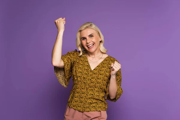 Happy blonde woman in blouse having menopause and rejoicing on purple — Foto stock