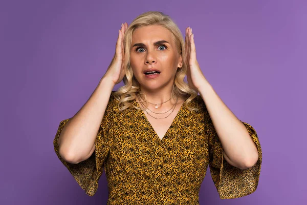 Shocked blonde woman stressing because of menopause isolated on purple — Stock Photo