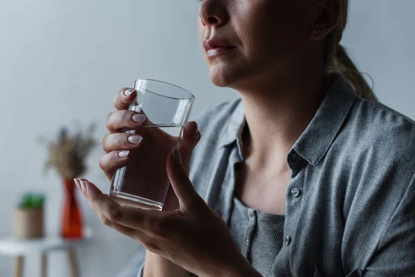 Обрізаний вид сумної жінки з кульмінацією, що тримає склянку води — стокове фото