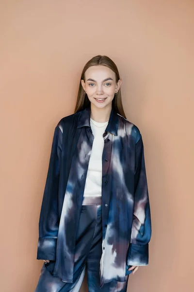 Femme heureuse en vêtements oversize de style tie-dye regardant la caméra isolée sur beige — Photo de stock