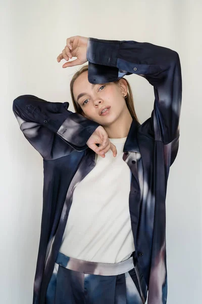 Young woman in trendy gradient shirt looking at camera while posing on white background — Photo de stock