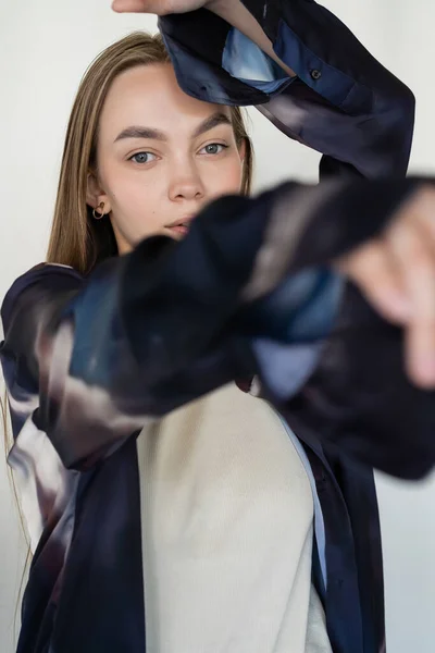 Mulher em camisa gradiente elegante olhando para a câmera em primeiro plano desfocado isolado no branco — Fotografia de Stock