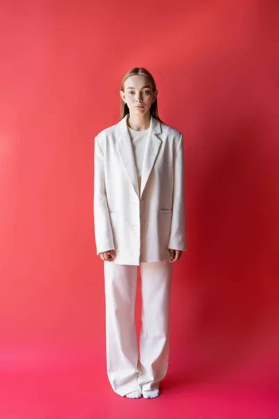 Pleine longueur de femme en costume blanc et chaussettes sur fond cramoisi — Photo de stock