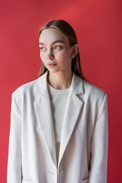 Encantadora mulher em branco oversize blazer olhando para longe isolado em carmesim — Fotografia de Stock