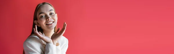 Joyful woman with hands near face looking at camera isolated on pink, banner - foto de stock