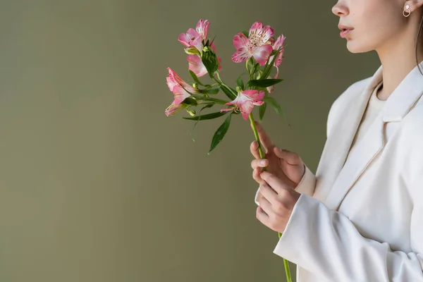 Cropped view of woman in white blazer holding alstroemeria flowers isolated on green — Foto stock