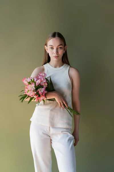 Mulher elegante em roupas brancas posando com buquê de alstroemeria isolado no verde — Fotografia de Stock