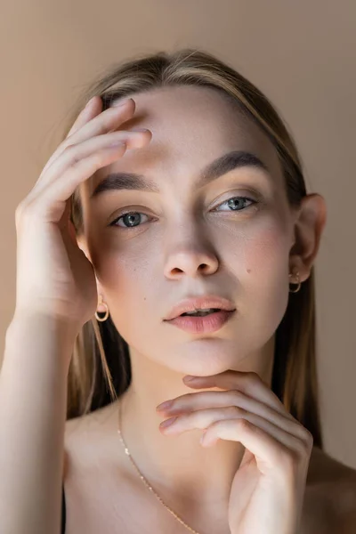 Portrait de jeune femme posant les mains près du visage propre isolé sur beige — Photo de stock