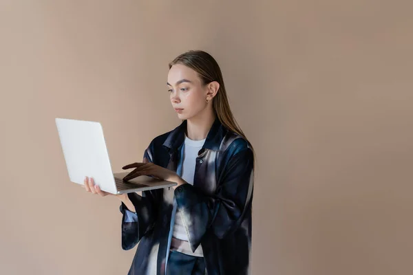 Frau im trendigen Gradienten-Hemd mit Laptop isoliert auf beige — Stockfoto