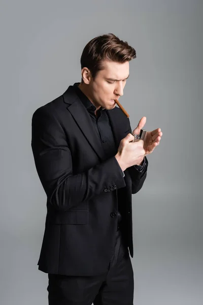 Man in black formal wear lighting cigar isolated on grey — Fotografia de Stock