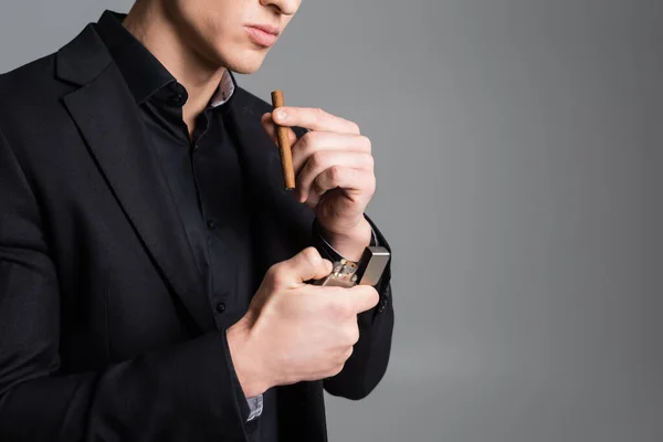 Partial view of man lightening cigar isolated on grey — Stock Photo