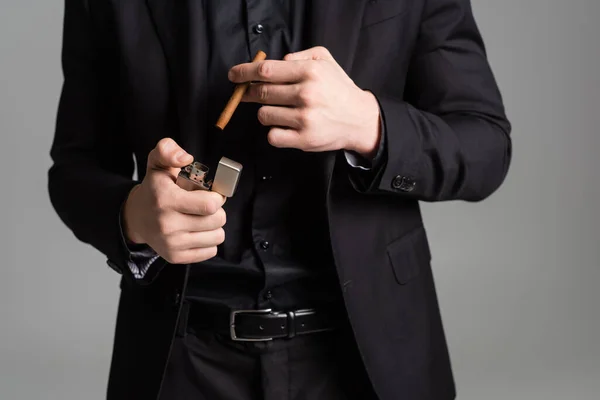 Vista cortada do homem em desgaste formal preto segurando isqueiro e charuto isolado em cinza — Fotografia de Stock