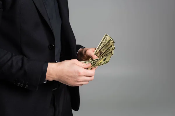 Partial view of man in black suit counting dollars isolated on grey — Photo de stock